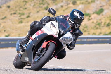 Motosikletli bir sürücü keskin bir viraj yapıyor. Fotoğraf 4 Temmuz 2021 'de Avila, Spai' deki Navalmoral limanında çekildi.