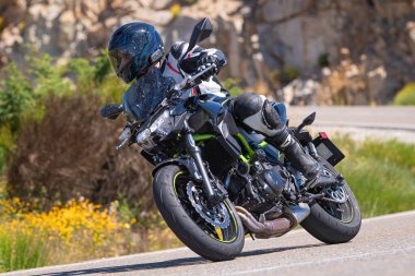 Motosikletli bir sürücü keskin bir viraj yapıyor. Fotoğraf 4 Temmuz 2021 'de Avila, Spai' deki Navalmoral limanında çekildi.