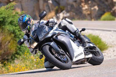 Motosikletli bir sürücü keskin bir viraj yapıyor. Fotoğraf 4 Temmuz 2021 'de Avila, Spai' deki Navalmoral limanında çekildi.