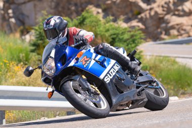 Motosikletli bir sürücü keskin bir viraj yapıyor. Fotoğraf 4 Temmuz 2021 'de Avila, Spai' deki Navalmoral limanında çekildi.