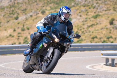 Motosikletli bir sürücü keskin bir viraj yapıyor. Fotoğraf 4 Temmuz 2021 'de Avila, Spai' deki Navalmoral limanında çekildi.