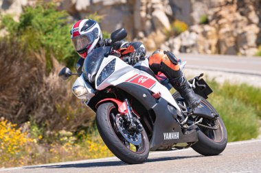 Motosikletli bir sürücü keskin bir viraj yapıyor. Fotoğraf 4 Temmuz 2021 'de Avila, Spai' deki Navalmoral limanında çekildi.