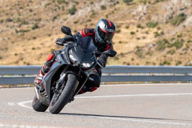 Motosikletli, aracıyla dağlardan geçiyor.