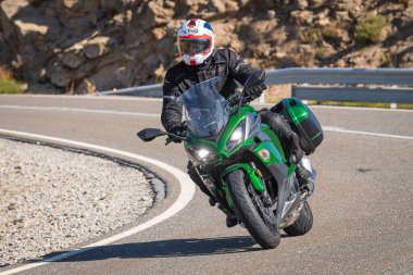 Motosikletli, aracıyla dağlardan geçiyor.