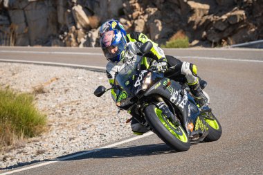 Motosikletli, aracıyla dağlardan geçiyor.