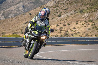 Motosikletli, aracıyla dağlardan geçiyor.