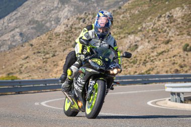 Motosikletli, aracıyla dağlardan geçiyor.