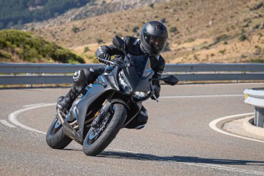 Motosikletli, aracıyla dağlardan geçiyor.