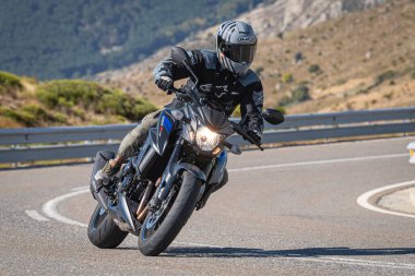 Motosikletli, aracıyla dağlardan geçiyor.