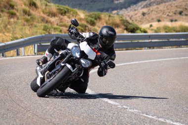 Ağustos 2020 'de İspanya' nın Avila ilindeki Navalmoral limanında güneşli bir pazar günü keskin bir viraj alan motosikletçi