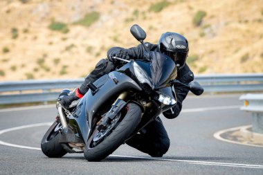 Keskin bir virajda motosikletinin kontrolünü kaybeden bir adam.