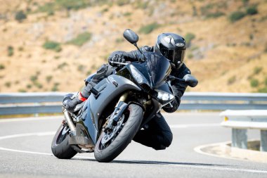 Keskin bir virajda motosikletinin kontrolünü kaybeden bir adam.