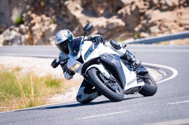 Ağustos 2023 'te Puerto de Navalmoral, vila' da motosikletli bir adam sıkı viraj alıyor.