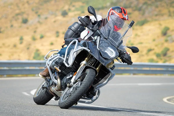 Keskin bir virajda motosikletinin kontrolünü kaybeden bir adam.