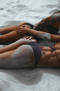 Beyaz kumsalda bikinili iki seksi kadın poposu. Spor, aktivite, tatilde dinlenme. Arkadaşlık ve yaşam tarzı