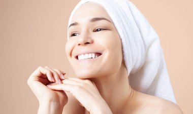 Bej arka planda saçında havlu olan tatlı bir kız. Temizleme, nemlendirme, yüz derisi için kurs.