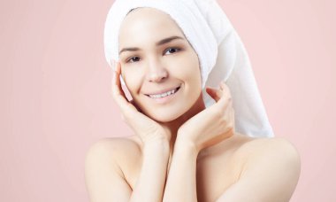 Pembe arka planda saçında havlu olan tatlı pozitif bir kız. Temizleme, nemlendirme, yüz derisi için kurs.