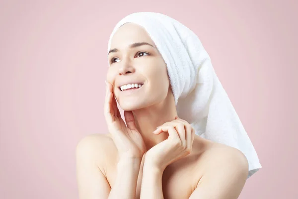 ピンクの背景に髪にタオルでかわいい肯定的な女の子 クレンジング 顔の皮膚のためのコース — ストック写真