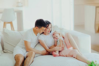 Baba, anne ve küçük oğlu oturma odasındaki kanepede dinleniyorlar. Çocuk bakımı ve ebeveynlik