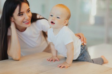 Annesi ona bakarken küçük bebek masada oturuyor. Bebek bakımı ve annelik