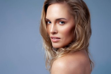 Dalgalı saçları olan güzel bir sarışın. Cilt bakımı, çıplak makyaj