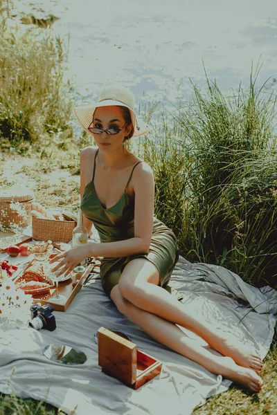 Beautiful young woman in hat with glass of white wine in nature. Lifestyle, outdoor recreation on weekends