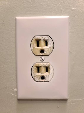 Yeşil boyalı bir duvara monte edilmiş iki prizi olan beyaz elektrik prizi..