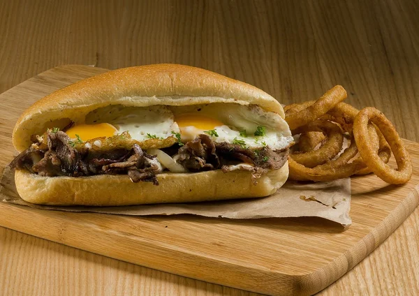 Steak and eggs sandwich with onion rings — Stock Photo, Image