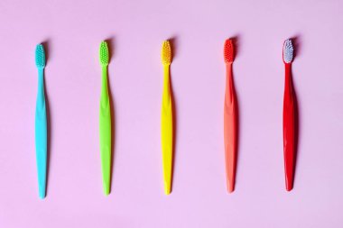 Leylak pembesi arka planda uzanan bir çok farklı canlı renkte diş fırçalarının üst görüntüsü. Boşluğu kopyala.