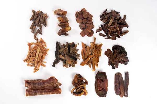 Various dehydrated beef and chicken products for dogs (trachea, noses, ears, necks, cut lungs, udder, liver, heart, stomach, testes and penis). Homemade pet treats. White background, copy space.