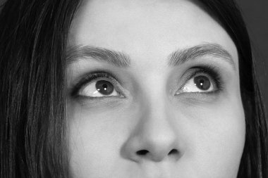 Güzel bir kadının yüzünün üst kısmının olduğu akromatik yakın plan bir portre. Siyah saçlı, badem şekilli gözleri, koyu tenli, yukarı bakan. Boşluğu kopyala.