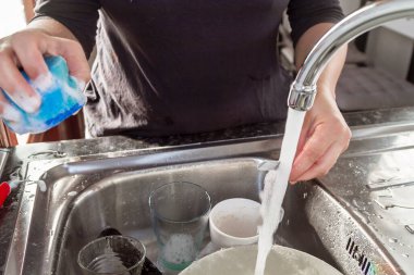 Mutfakta bulaşık yıkayan bir kadın.