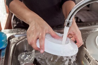 Mutfakta bulaşık yıkayan bir kadın.