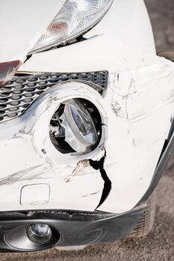 Yoldaki bir kazadan sonra arabanın teftişi. Araba kazası ya da kaza. Ön kanat ve sağ far kırılmış, tamponda hasar ve çizikler var. Kırık araba parçaları ya da yakın çekim.