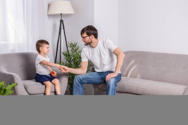 Baba ve küçük oğlu evdeki oturma odasında ciddi bir şey tartışıyorlar. Güven ailesi. İlişki psikolojisi.