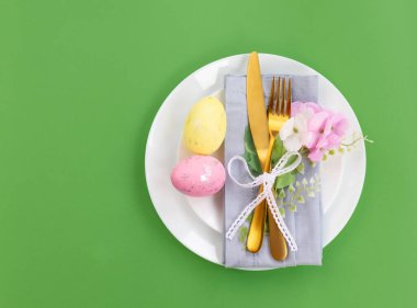 Mutlu Paskalyalar. Paskalya kutlaması. Üst manzara dikey peçete boş beyaz ve sarı plaka, paskalya yumurtaları, izole edilmiş yeşil arka plan. Boşluğu kopyala, metin için yer, pankart.