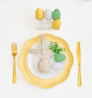 Mutlu Paskalyalar. Paskalya kutlaması. Dikey beyaz, sarı tabak, dekoratif tavşan, yumurta, izole beyaz arka plan. Boşluğu kopyala, metin için yer, pankart.