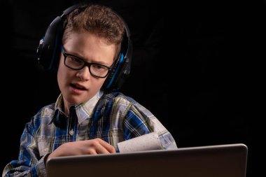 Çocuk dizüstü bilgisayarın önünde gömlekten pamuk çıkarıyor.