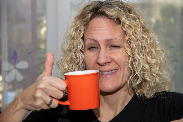 Woman with cup and thumbs up