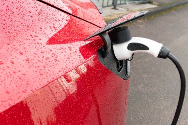 Kırmızıyla yağmur damlası olan elektrikli araba fiş ile şarj edilir