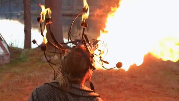 Человек с длинными волосами плюется огнем возле озера — стоковое видео