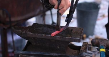 Dişi eller kanca yapmak için demir çubuk dövüyor