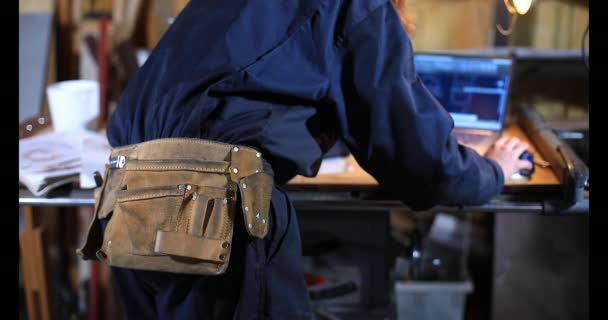 Female craftswoman with work belt using laptop — Stock Video