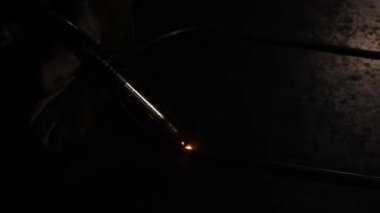 Çubuğun köşelerini birleştirmek için elektrot kullanan kadın