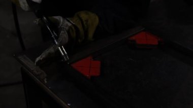 Çubuğun köşelerini birleştirmek için elektrot kullanan kadın