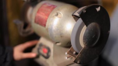 Dönen değirmen taşıyla çubuk parlatan kadın