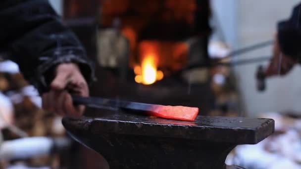 Hands hitting hammer on iron rod on anvil — Stock Video