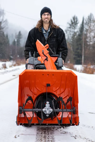 Young man playing with a snowplough in the winter — Stock Photo, Image