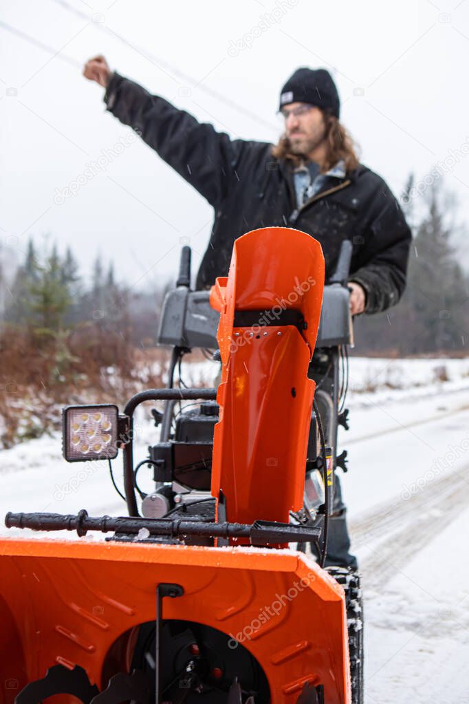 Young man playing with a snowplough in the winter