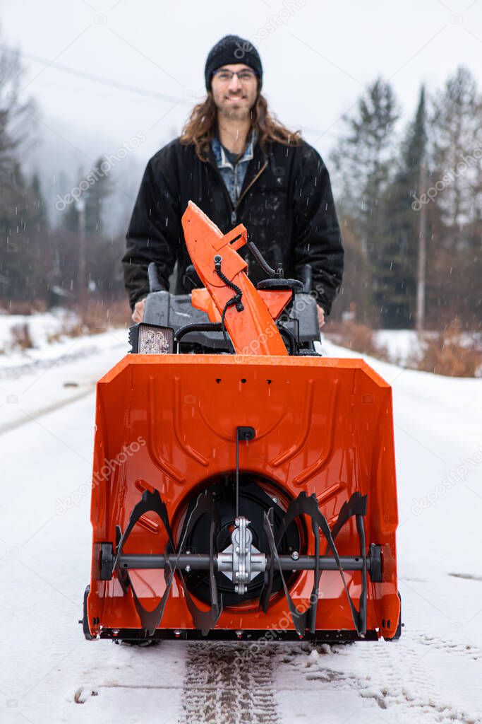 Young man playing with a snowplough in the winter